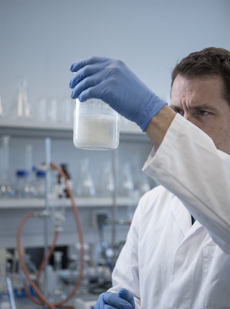 Profesional de laboratorio examinando una emulsión cosmética a contraluz