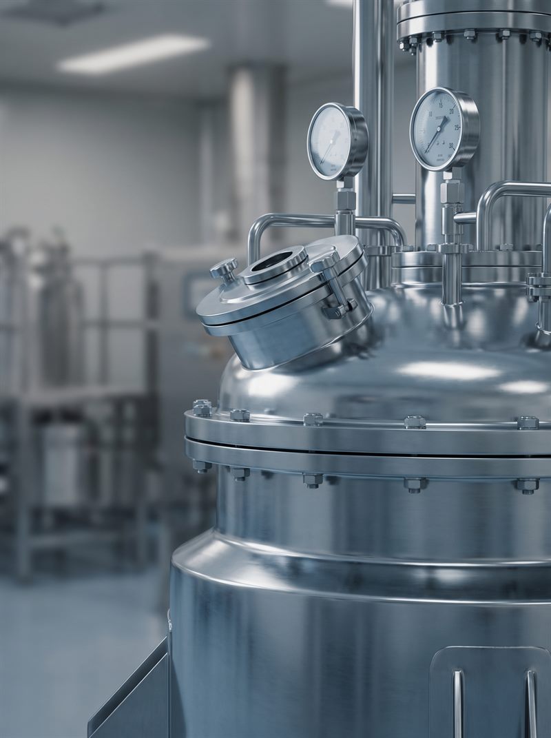 Reactor de acero inoxidable con manómetros en sala de producción